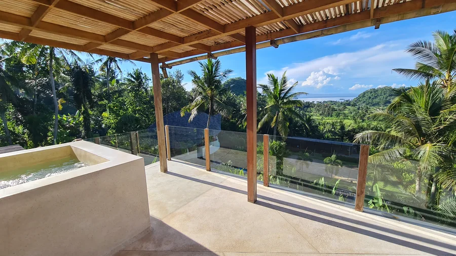 Überdachte Hotelterrasse mit Blick über Palmen bis zum Meer in Ostbali